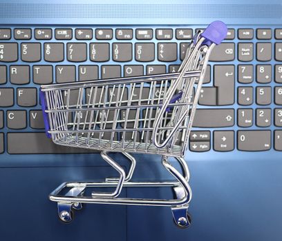 A miniature shopping cart on a laptop keyboard representing an online darknet marketplace
