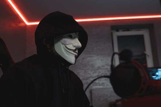 A hooded figure at a dimly lit computer, illustrating anonymous access to Tor hidden services